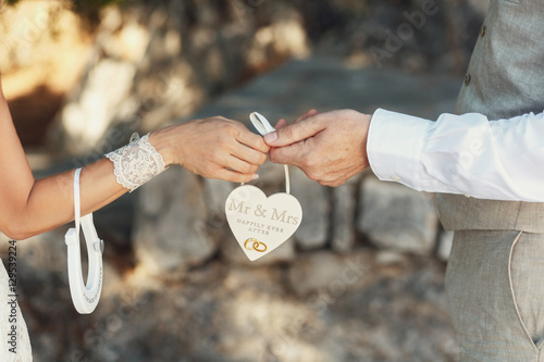 Bride and groom in grey suit hold paper heart with lettering 'Mr