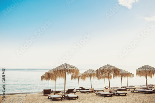 Fototapeta Naklejka Na Ścianę i Meble -  Beach umbrellas stand over wooden beds on sand