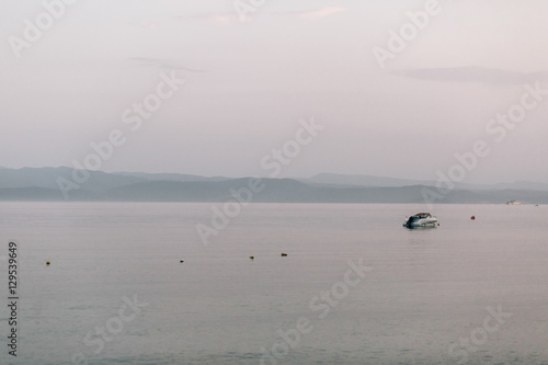 Lonely boat floats in the sea under grey sky