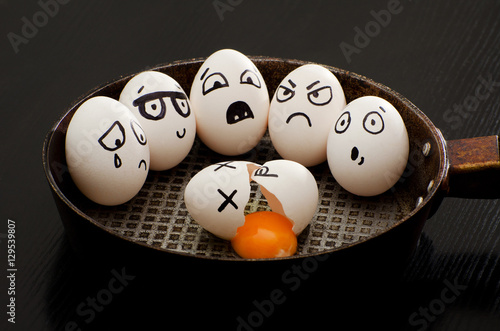 Broken egg in a pan surrounded by whole eggs with different emotions