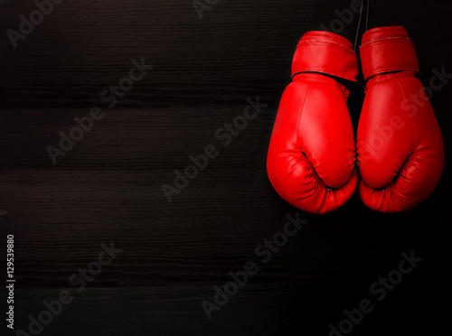 Two red boxing gloves in the upper corner of the frame over a black background, empty space