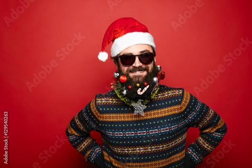 Cool man dressed as Santa Claus over red background