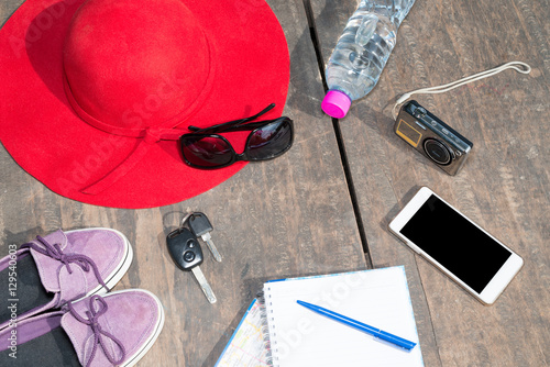 Preparation for travel,trip vacation, tourism mock up of cell phone,camera,hat,shoes,sunglasses,drinking water, notebook, map on wooden table Essential vacation items, Travel concept background