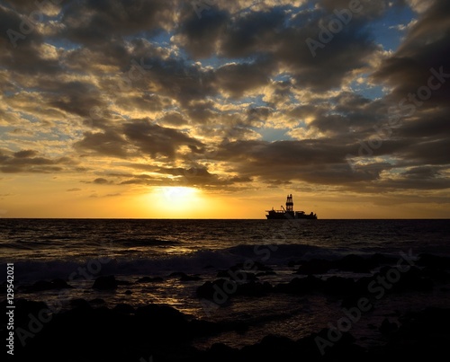 Amazing sunrise from the seashore with low clouds and oil rig in background