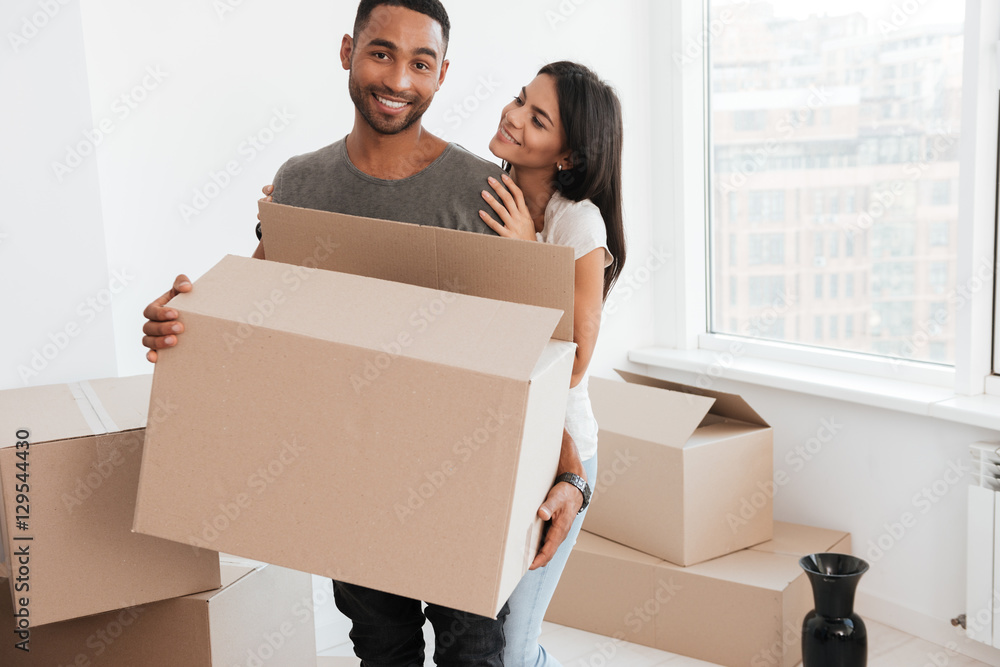 Loving couple standing with unpacked boxes in room Loving couple standing with unpacked boxes in room