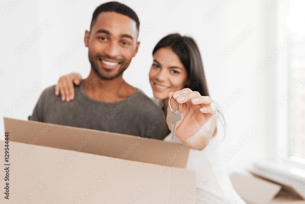 Happy couple standing with unpacked box and holding key. Happy couple standing with unpacked box and holding key.