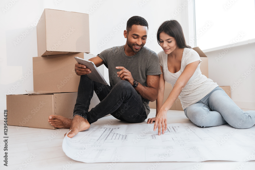 Couple planning decoration at new home sitting on the floor Couple planning decoration at new home sitting on the floor