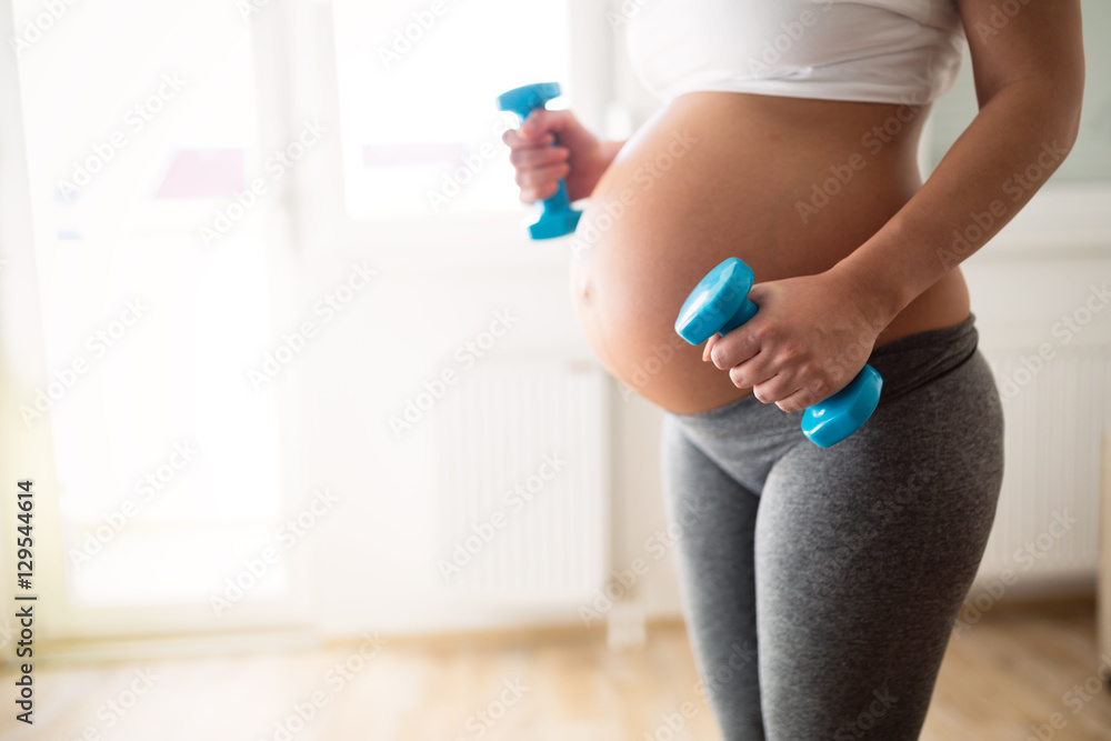 Pregnant woman training with dumbbells Pregnant woman training with dumbbells
