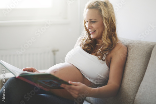 Pregnant woman reading book on sofa