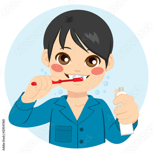 Cute boy brushing his teeth and holding toothpaste
