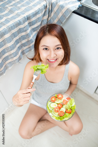 Beautiful young asian girl eating salad. smiling happy girl eati photo