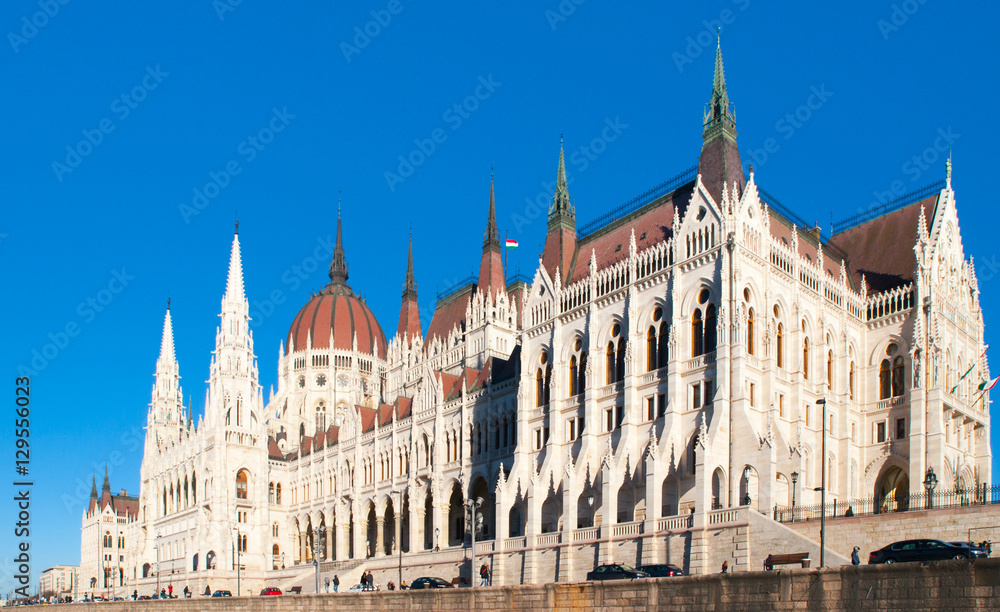 Fototapeta premium Daytime view of historical building of Hungarian Parliament, aka Orszaghaz, with typical symmetrical architecture and central dome on Danube River embankment in Budapest, Hungary, Europe. It is