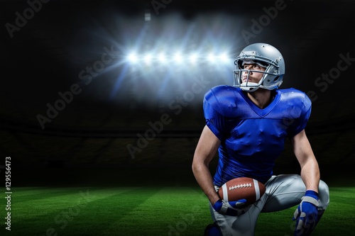 Composite image of american football player with ball kneeling