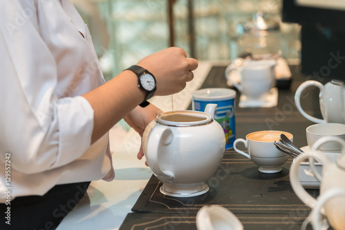 The waitress is pouring tea in the restaurant 