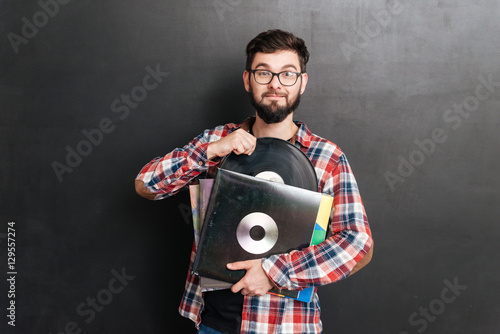 Cheerful man over chalkboard holding vinyl records in hands