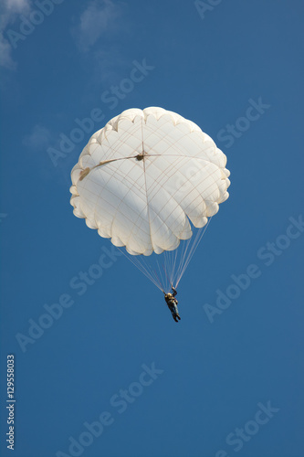 White round parachute on background blue sky.