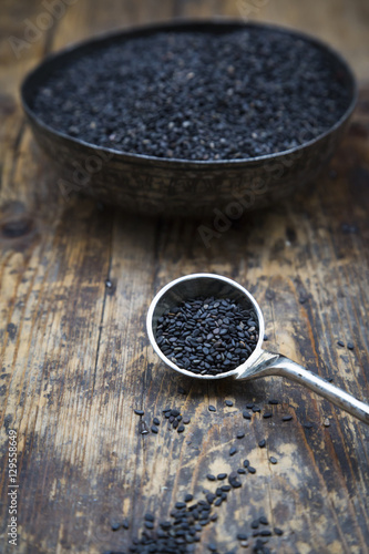 Mass and bowl of organic black sesame on dark wood photo