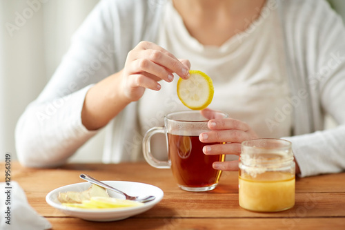 close up of ill woman drinking tea with lemon