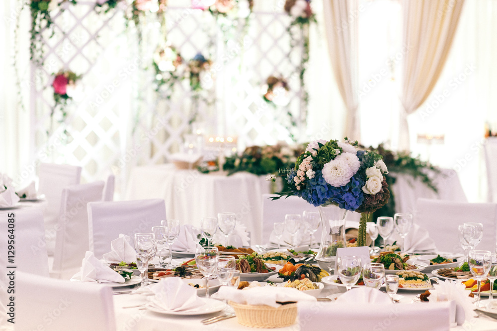 Bouquet of white and blue flowers stands on white table in brigh Bouquet of white and blue flowers stands on white table in brigh
