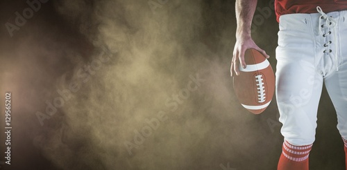 Composite image of american football player holding up football © vectorfusionart