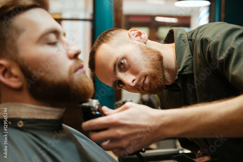 Handsome man getting beard haircut by bearded hairdresser © Drobot Dean