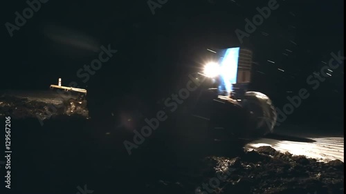 Late ploughing at the end of November in heavy snowfall. Tractor plowing.