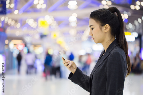 Female walking through the airport using her smartphone device.
