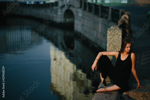 young and graceful woman sitting near the river alone