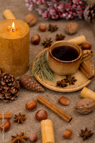 Cup of coffee, cookies, walnuts, hazelnuts, cinnamon sticks, star anise, cone, candle, fir branch on sackcloth fabric © shmelevevgeniy