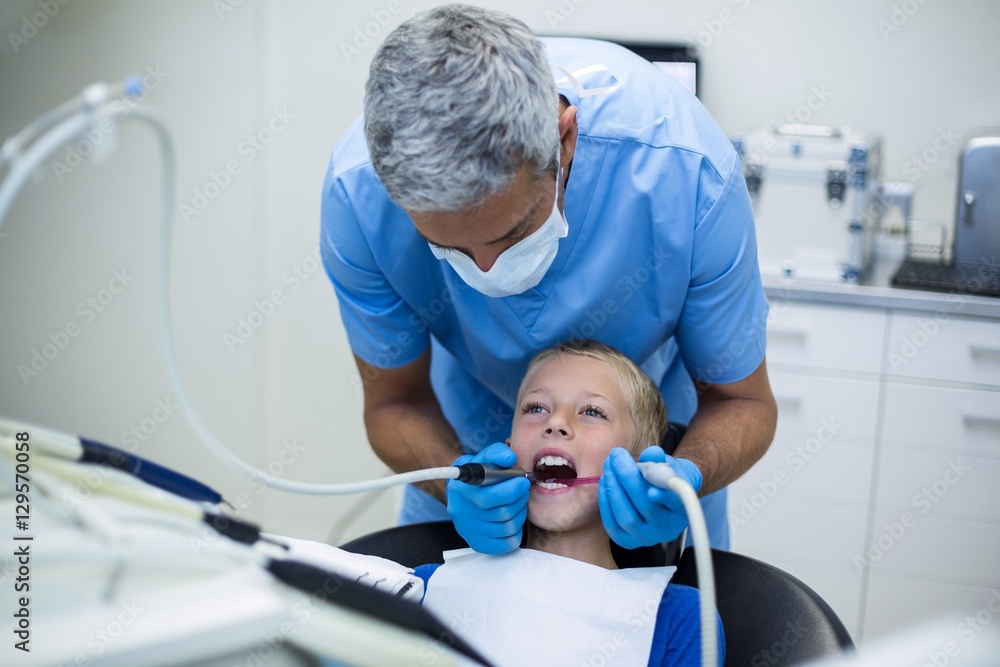 Dentist examining a young patient with tools Dentist examining a young patient with tools