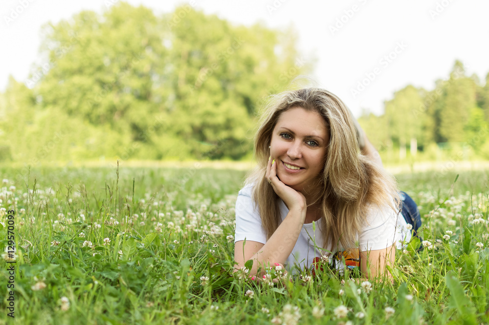 Beautiful woman lying on a field of clover, happy girl resting in a meadow, relaxation outdoors in spring time, vacation concept Beautiful woman lying on a field of clover, happy girl resting in a meadow, relaxation outdoors in spring time, vacation concept