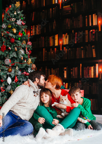 The charming family with cat sitting near Christmass Tree