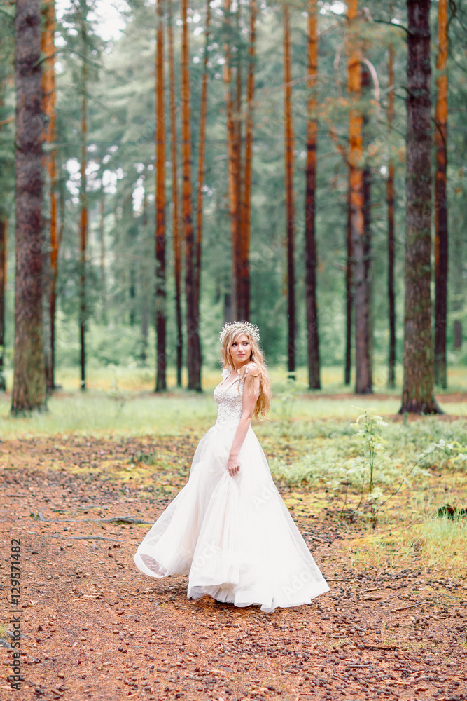 Bride in wedding dress walking in the forest. Bride waiting for groom.