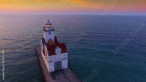 Stunning sunrise over illuminated lighthouse, aerial view.
 photo