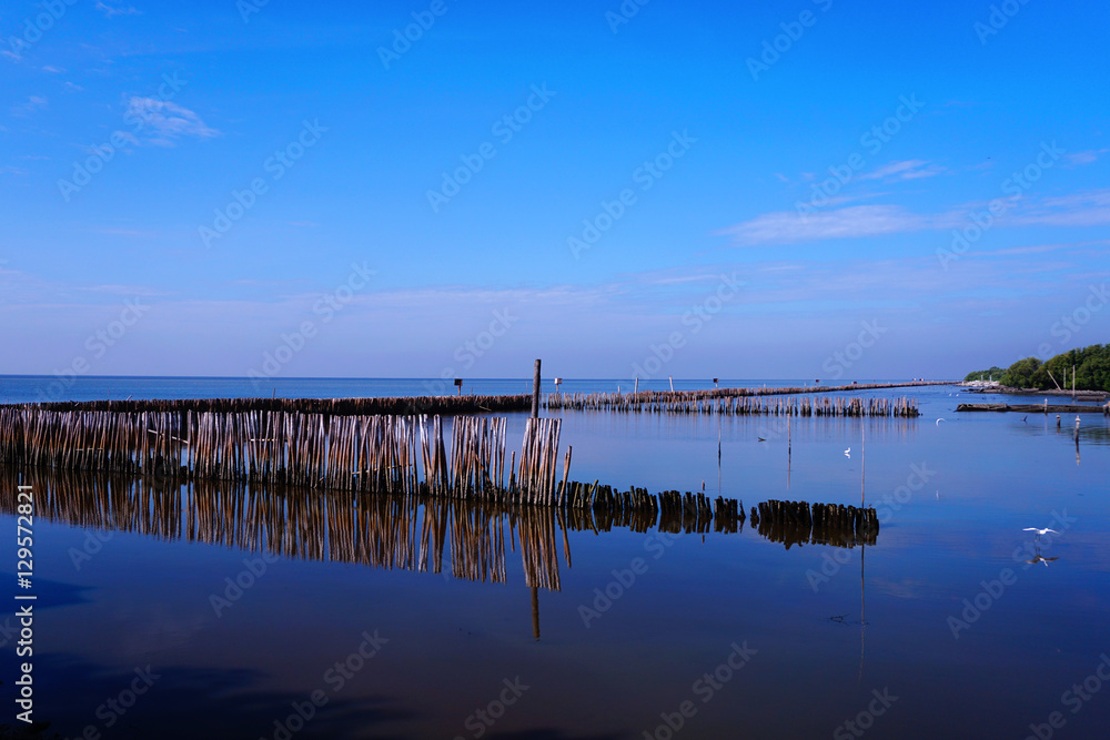 Long simple wooden jetty leading into blue ocean in the gulf of Thailand with sunset