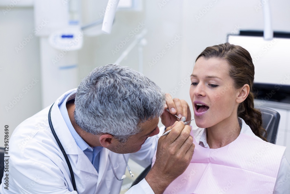 Dentist examining a female patient with tools Dentist examining a female patient with tools