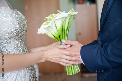 руки жениха и невесты держат букет