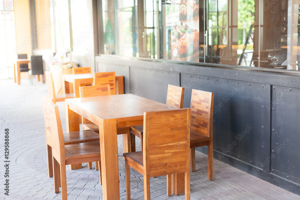 Outdoor wooden table and chair in front of restaurant. Soft focus and over lighting flares.
