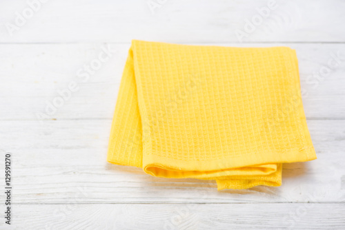 Yellow napkin isolated on white wooden table. Copy space. Top view.
