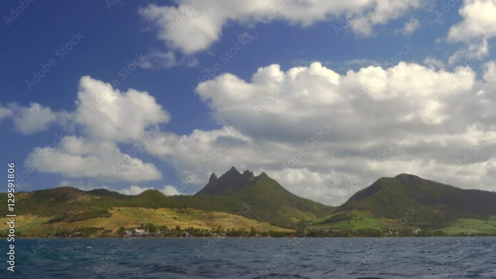 View from sailing ship to Mauritius Island scene with green hills and forested mountains View from sailing ship to Mauritius Island scene with green hills and forested mountains