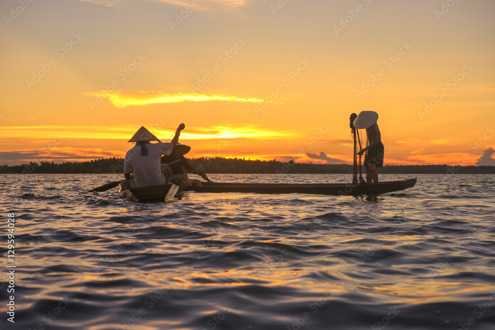 Silhouette of traditional fisherman throwing net fishing lake at sunrise time