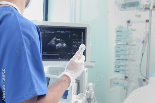 Male doctor with an ultrasound sensor in hand examining patient