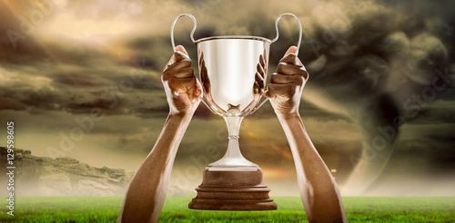 Composite image of cropped hand of athlete holding trophy 3D