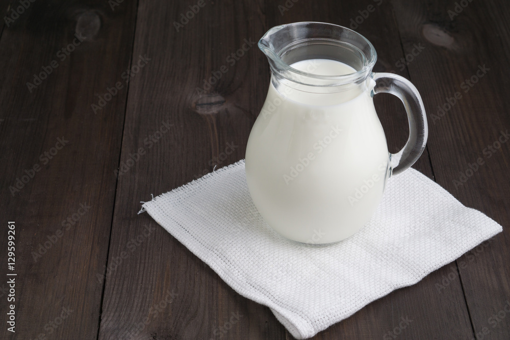 full jug of milk on white tissue napkin and wooden background full jug of milk on white tissue napkin and wooden background