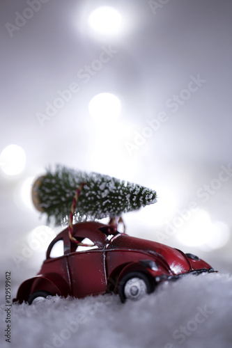 A miniature red car carrying a christmas tree