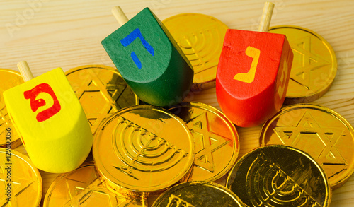 Close up of wood dreidels and chocolate coins for Hanukkah celebration. Caps following words : 