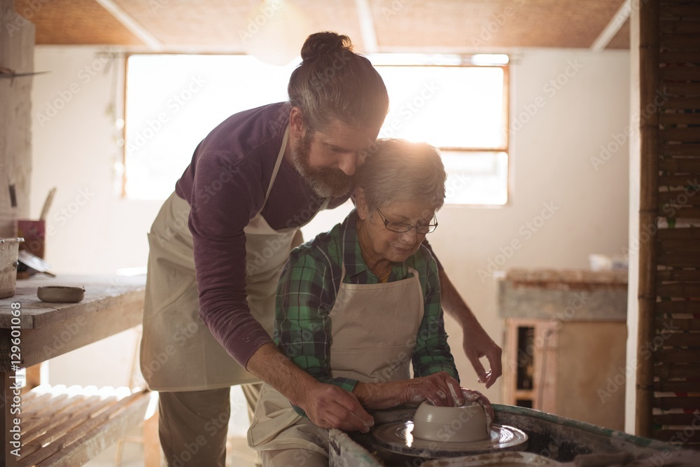 Male potter assisting female potter Male potter assisting female potter