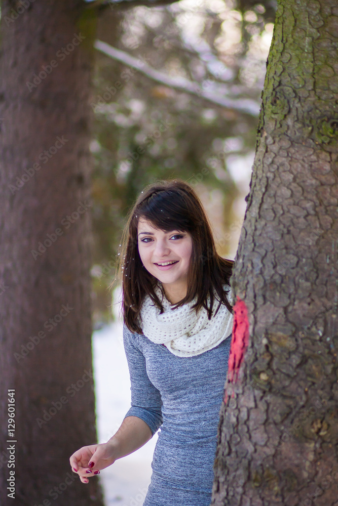 Smiling girl looks out from behind a tree Smiling girl looks out from behind a tree