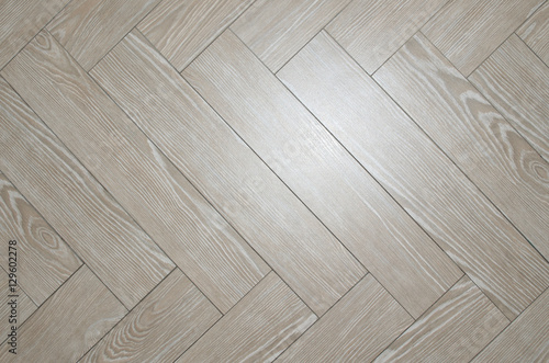 Beige floor tiles arranged in herringbone with look of parquet