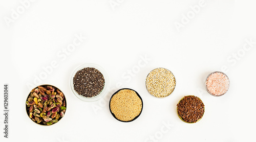 Various superfoods on a white background. Pistachio nuts, chia seeds, amarant, quinoa, flex seeds, rose salt. Copy space for text